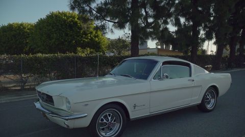 1993 Ford Taurus - A classic white Ford Mustang Fastback is parked on the side of the road under a clear sky.
