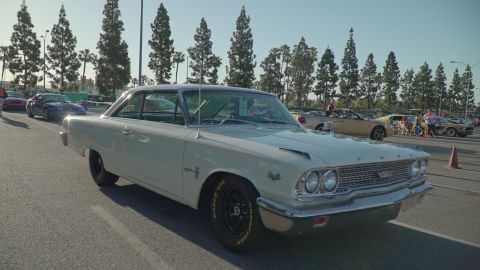1993 Ford Taurus - A white 1963 Ford Galaxie 500 is parked at an outdoor car show, with other vehicles visible in the background.