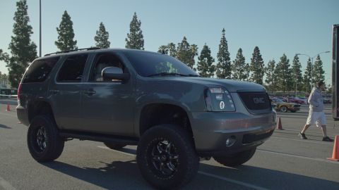 1993 Ford Taurus - A lifted GMC Yukon XL is parked outdoors with other vehicles and a person walking nearby.