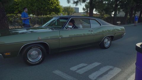 1993 Ford Taurus - A classic green Ford Galaxie is seen from the side, with a driver behind the wheel.