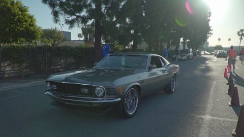 1993 Ford Taurus - A classic Ford Mustang is seen driving down a street, possibly at a car show event.