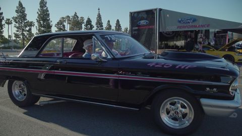 1993 Ford Taurus - A black 1963 Ford Falcon is parked near a Ford Performance trailer, with a yellow car visible in the background.