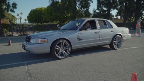 1993 Ford Taurus - A silver sedan, possibly a Ford Crown Victoria, is seen from the side with custom rims and a light bar on the roof.