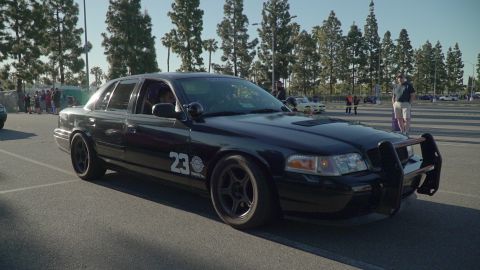 1993 Ford Taurus - This black sedan, likely a Ford Crown Victoria, is equipped with a push bar and racing decals.