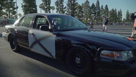 1993 Ford Taurus - Modified police car with X markings on the door, seen at an outdoor event.