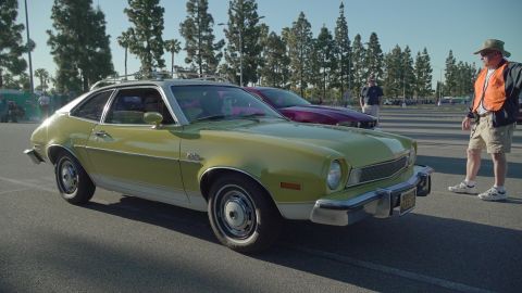 1993 Ford Taurus - A yellow 1975 Ford Pinto coupe is parked at an outdoor car show with another vehicle behind it.