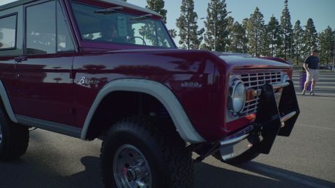 1993 Ford Taurus - A classic maroon Ford Bronco is parked at an outdoor event.