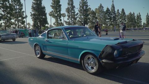 1993 Ford Taurus - A teal 1965 Ford Mustang Fastback is seen from the front-right at an outdoor car show.