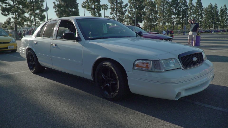 White sedan with black wheels, front quarter view, showing modified front bumper and grille