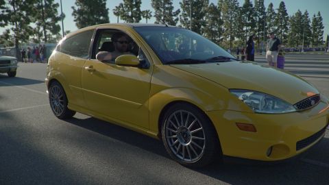 1993 Ford Taurus - A yellow 2000 Ford Focus hatchback is seen from the front-right at a car show.