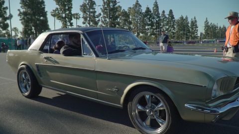 1993 Ford Taurus - A classic 1965 Ford Mustang coupe is seen from the side at an outdoor car event.