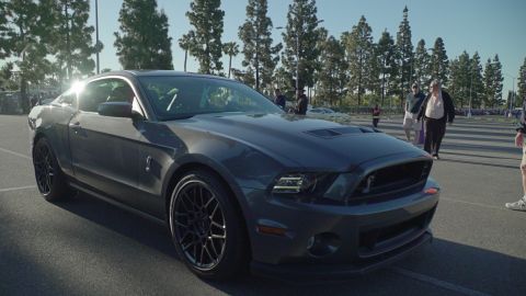 1993 Ford Taurus - A dark gray 2010 Ford Mustang Shelby GT500 is parked at an outdoor car show.