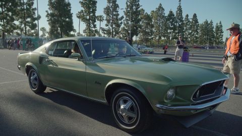 1993 Ford Taurus - A green 1969 Ford Mustang coupe is parked at an outdoor event with people in the background.