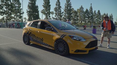 1993 Ford Taurus - Yellow hatchback with racing stripes and 'Hillbank Motorsports' decals is parked in an outdoor lot.