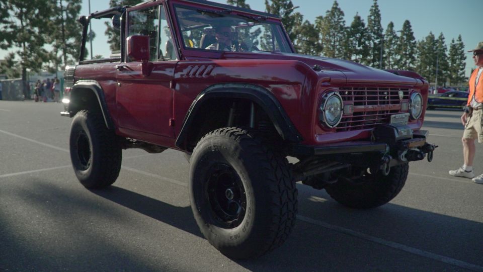 Red Ford Bronco with large off-road tires and a winch on the front bumper