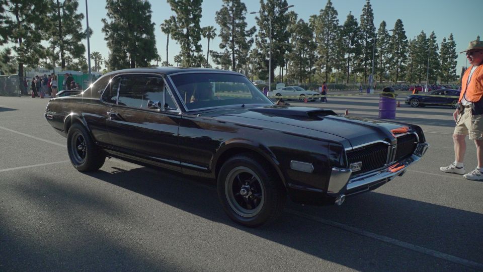 Black 1969 Mercury Cougar XR7 coupe with hood scoop and orange accents on grille