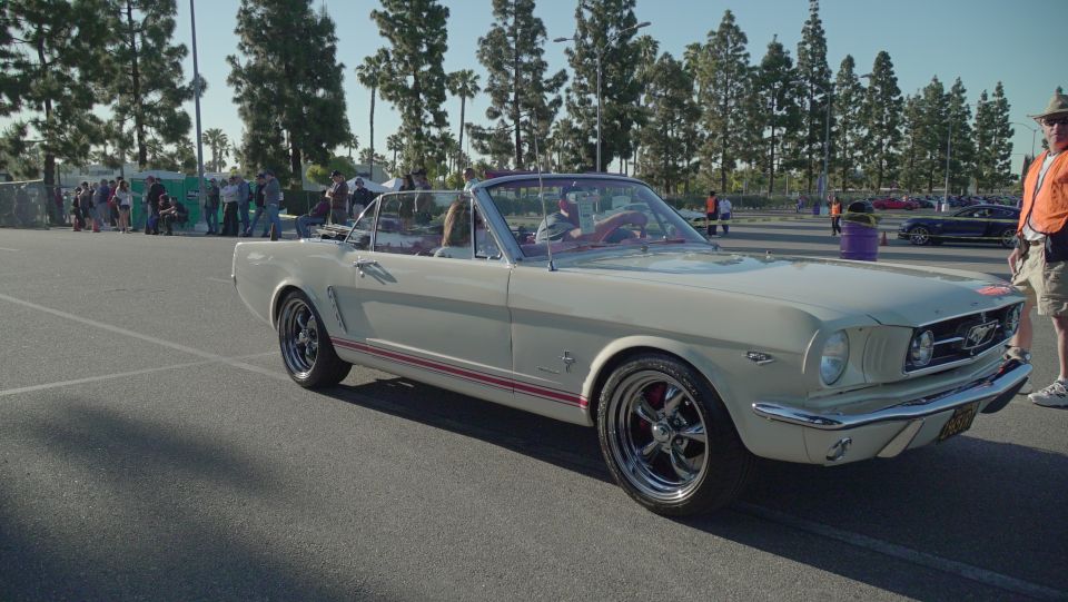 Cream 1965 Ford Mustang convertible with red stripe, chrome wheels, and red interior