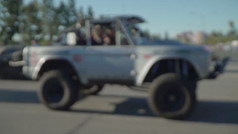 1993 Ford Taurus - A modified off-road vehicle with oversized tires and a roll cage is captured in motion.