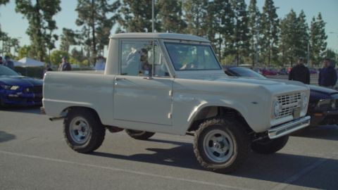 1993 Ford Taurus - A classic white Ford Bronco is parked at an outdoor car show.