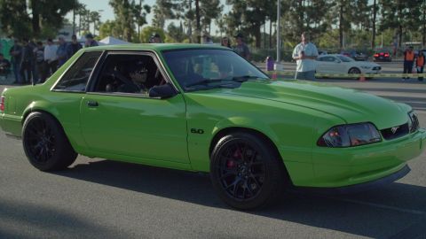 1993 Ford Taurus - A bright green Ford Mustang is parked at an outdoor car show with other vehicles and spectators in the background.