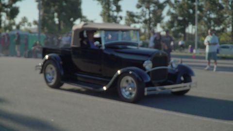 1993 Ford Taurus - A classic black pickup truck from the 1930s, a tan convertible top, cruises down the road.