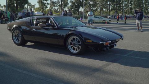 1993 Ford Taurus - A dark De Tomaso Pantera is seen from the front-right at a car show with other vehicles and spectators present.