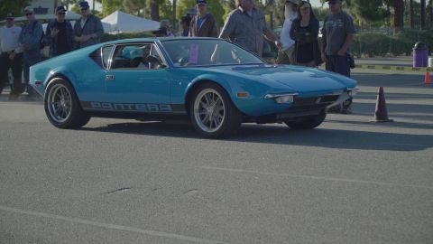 1993 Ford Taurus - A blue de Tomaso Pantera is parked at an outdoor car show, with people standing around it.