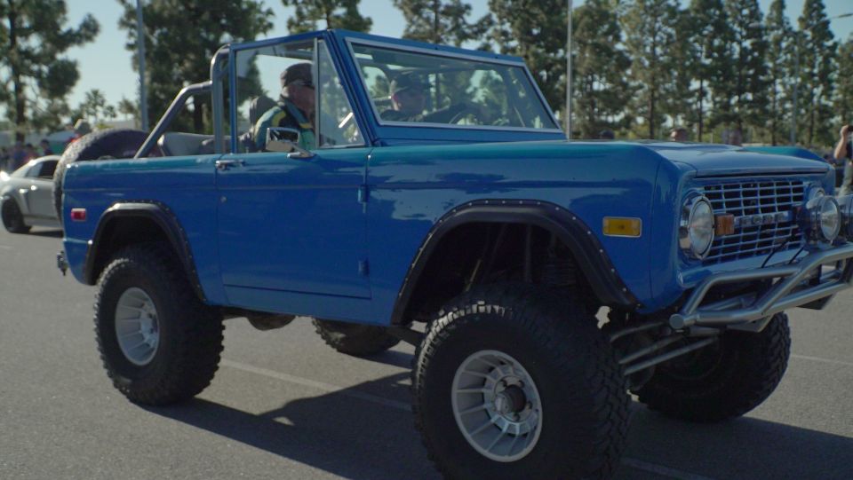 Lifted blue 1970s Ford Bronco with off-road tires and chrome grille