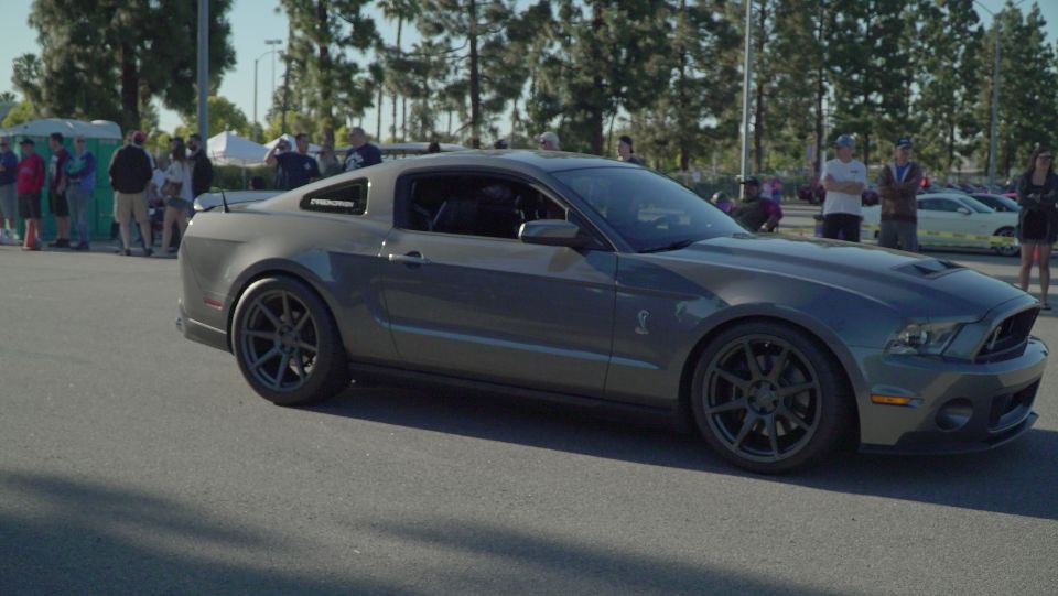 Dark gray Ford Mustang Shelby GT500 with black wheels and hood scoop, parked outdoors.