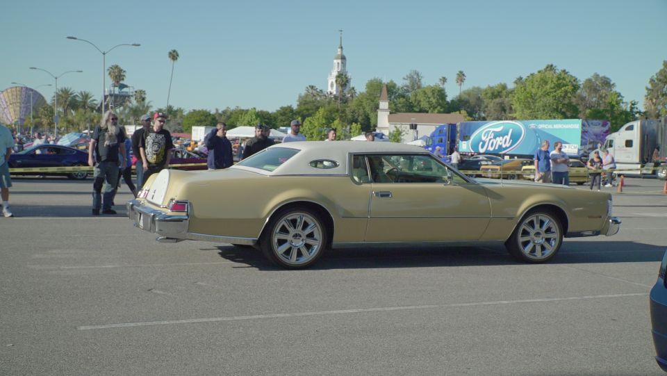Gold two-door coupe with white vinyl roof parked in an asphalt lot.