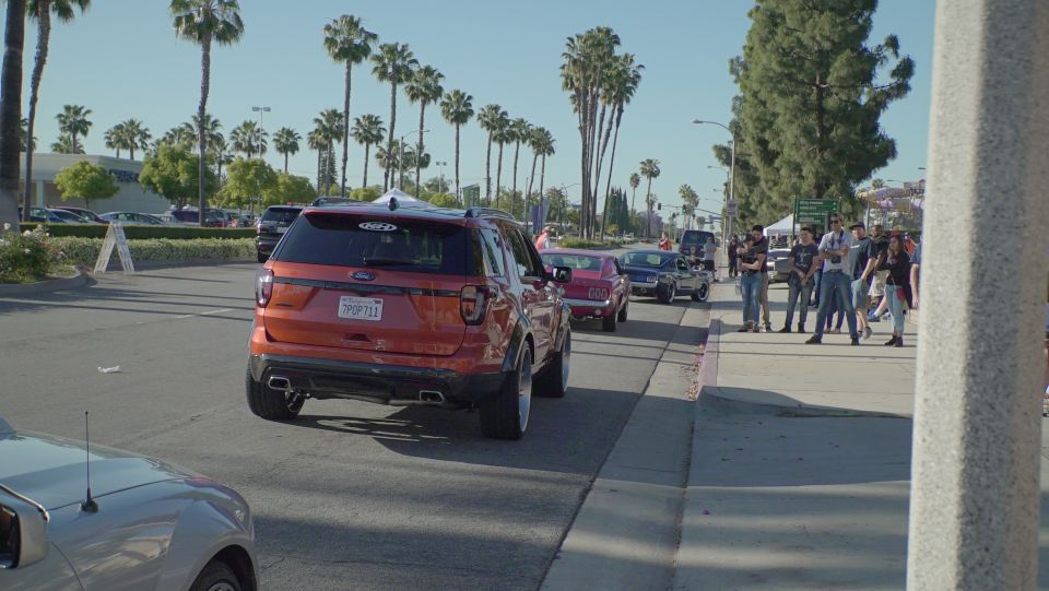 Orange Ford Explorer SUV with custom wheels and fender flares on a street.