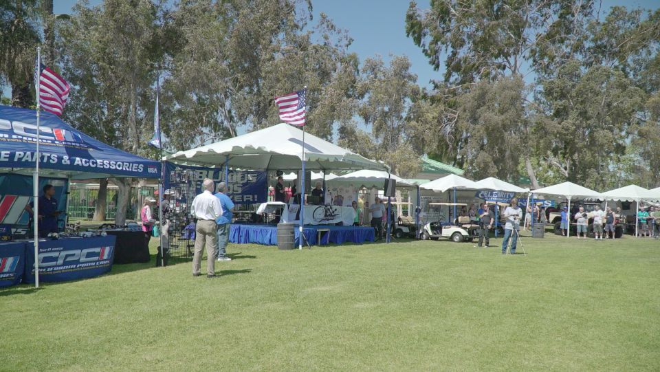 Outdoor event with tents, people, and golf carts.