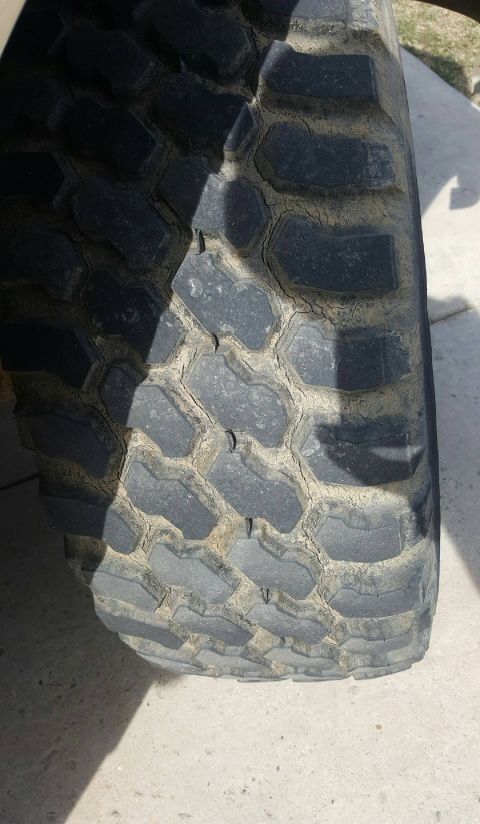 1995 Ford F-150 - A close-up view of a worn tire tread with visible cracking and dirt accumulation. The tire features a rugged, off-road pattern with large,…