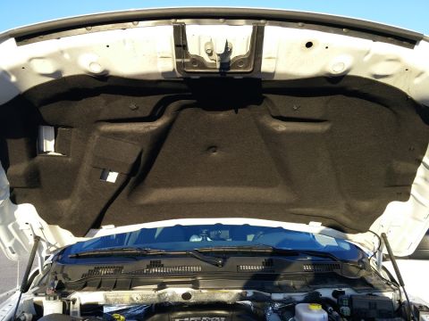 2000 Ford Crown Victoria - The underside of a white vehicle's hood is open, revealing black sound-dampening material. The engine bay and windshield wipers are visible…