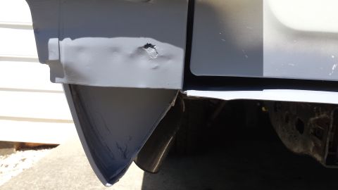 1976 Ford Ranchero - A close-up view of the rear corner of a vehicle, showing primer applied to a dented and damaged area of the body panel and bumper. A sectio…