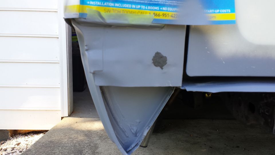 Vehicle's lower rear corner with primer and repair work.