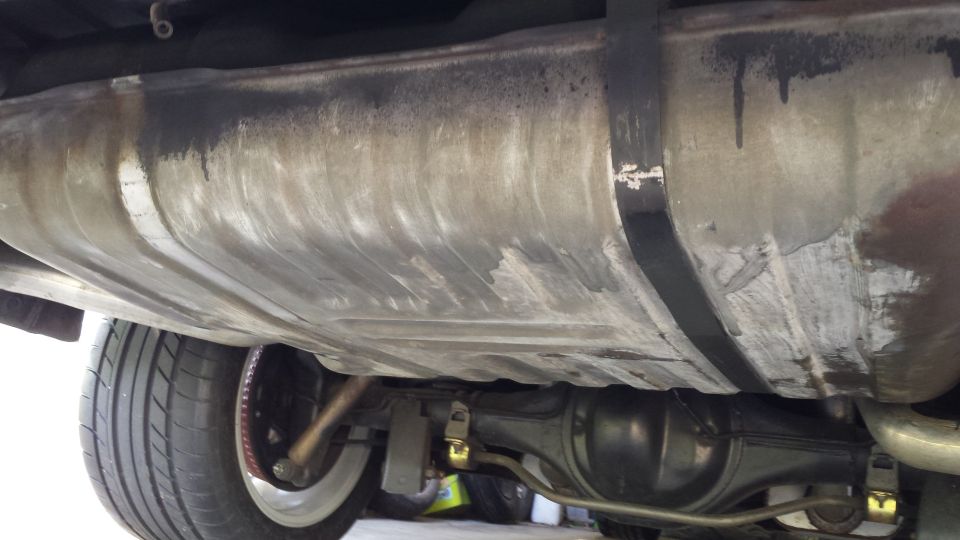 Undercarriage of a vehicle showing fuel tank, rear differential, and tire.