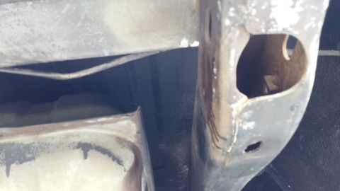 1976 Ford Ranchero - The underside of a vehicle shows a metal frame with a large oval cutout, revealing a dark interior. A fuel tank or similar component is vis…
