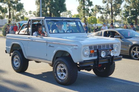 1993 Ford Taurus - A white 1970s Ford Bronco is parked at an outdoor car show, with another vehicle visible behind it.
