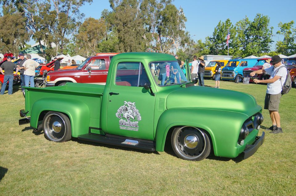 Green classic pickup truck with custom door graphic parked on grass.