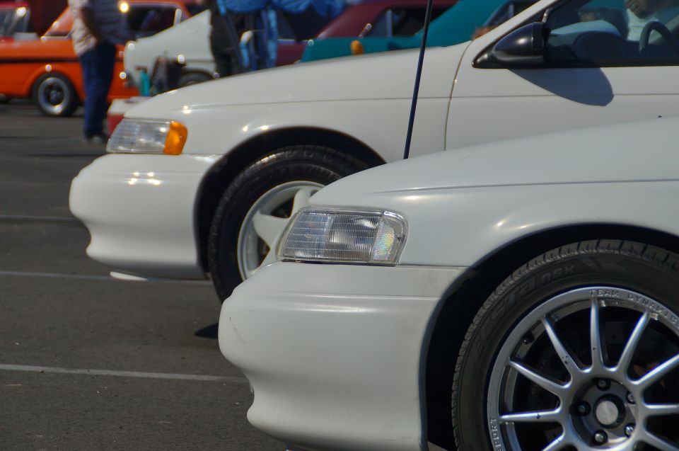 White sedan front quarter panel and headlight with silver aftermarket wheel