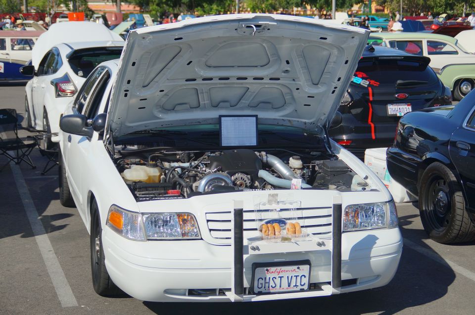 White Ford Crown Victoria with hood open, showing engine and "GHST VIC" license plate.