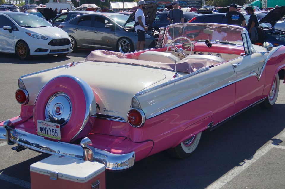 Pink and cream 1950s convertible classic car with rear spare tire and custom license plate.