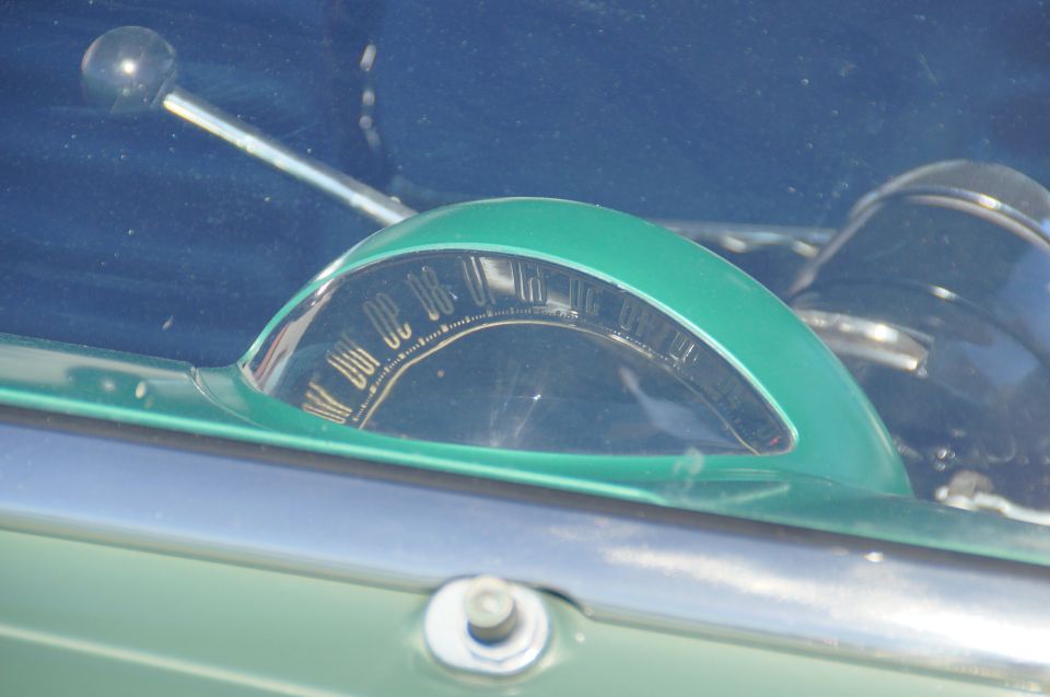 Vintage car dashboard with green shroud, speedometer, and chrome lever.