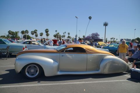 Custom silver and gold coupe with a unique roofline at a car show.