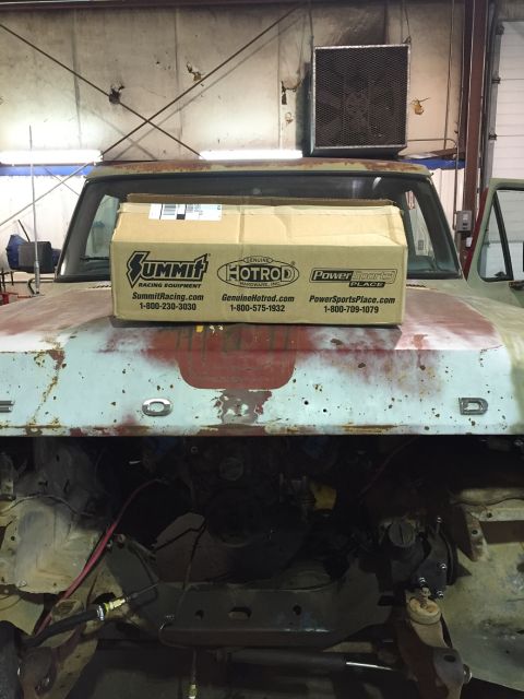 1978 Ford Bronco - A box from Summit Racing Equipment sits on the hood of a vintage Ford truck with its engine bay exposed. The truck's hood is faded and rust…