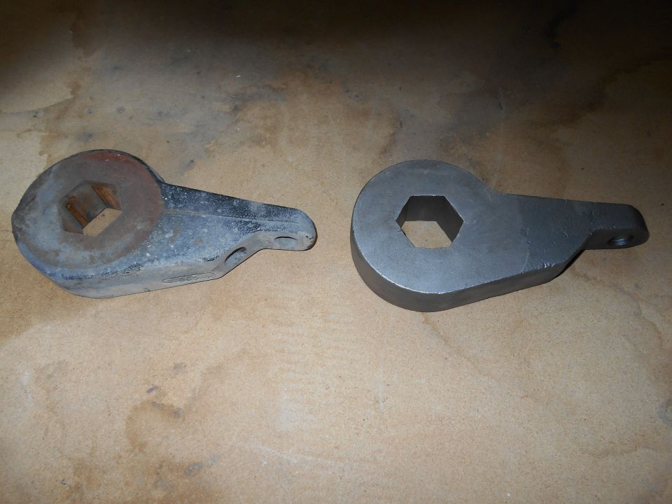 Two torsion bar keys, one old and rusted, one new and painted, on a textured surface.