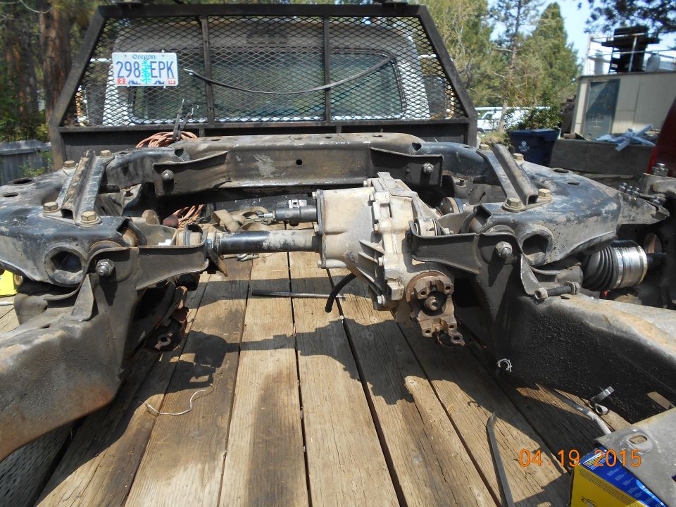 Disassembled front axle and differential assembly from a 1995 GMC Safari on a wooden surface.