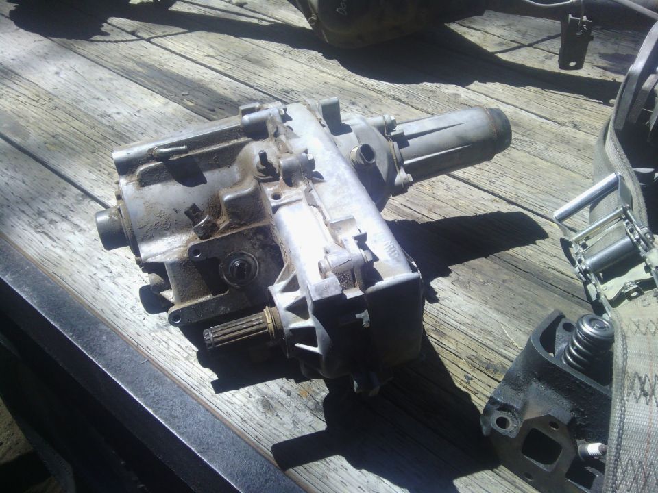 Transfer case and engine part on wooden surface with ratchet strap
