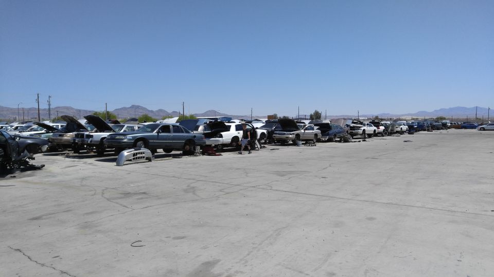 Junkyard with many cars parked, some with hoods open.